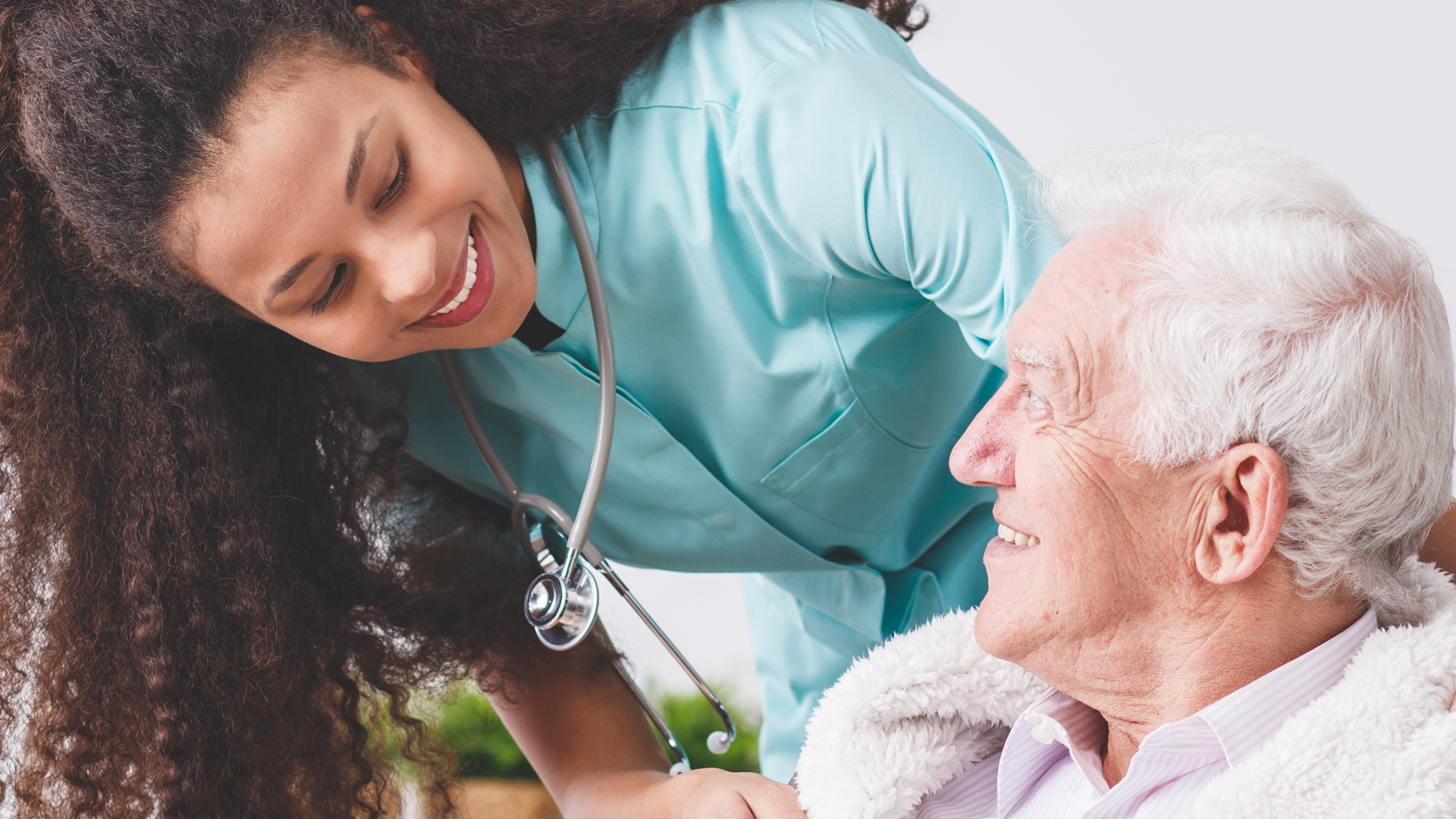 Panorama of a happy nurse with a stethoscope covering an elderly man with a blanket in a nursing home © photographee.eu - stockadobe.com