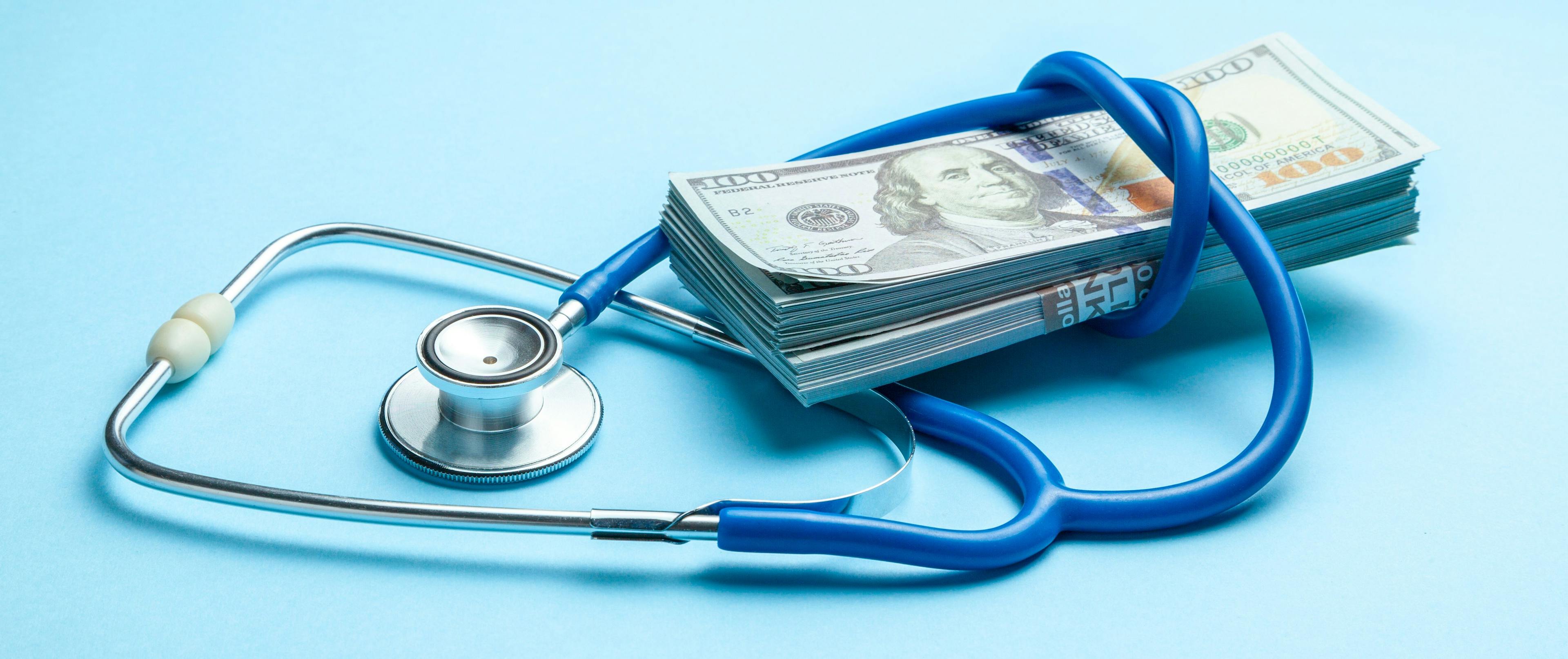 Stack of cash dollars and stethoscope on blue background. The concept of medical strechevka or expensive medicine, doctors salary | Image Credit: © adragan - stock.adobe.com 